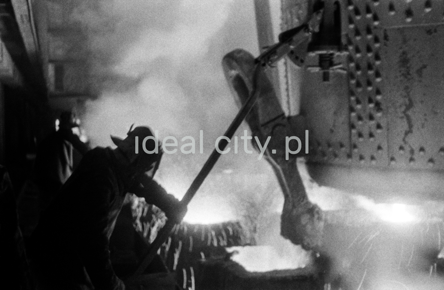 The uniformed steelworker leans over the sparkling vat.