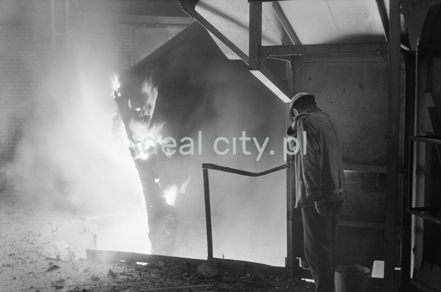 A man in denim and a work helmet looks down the sparkling vat from the metal deck.