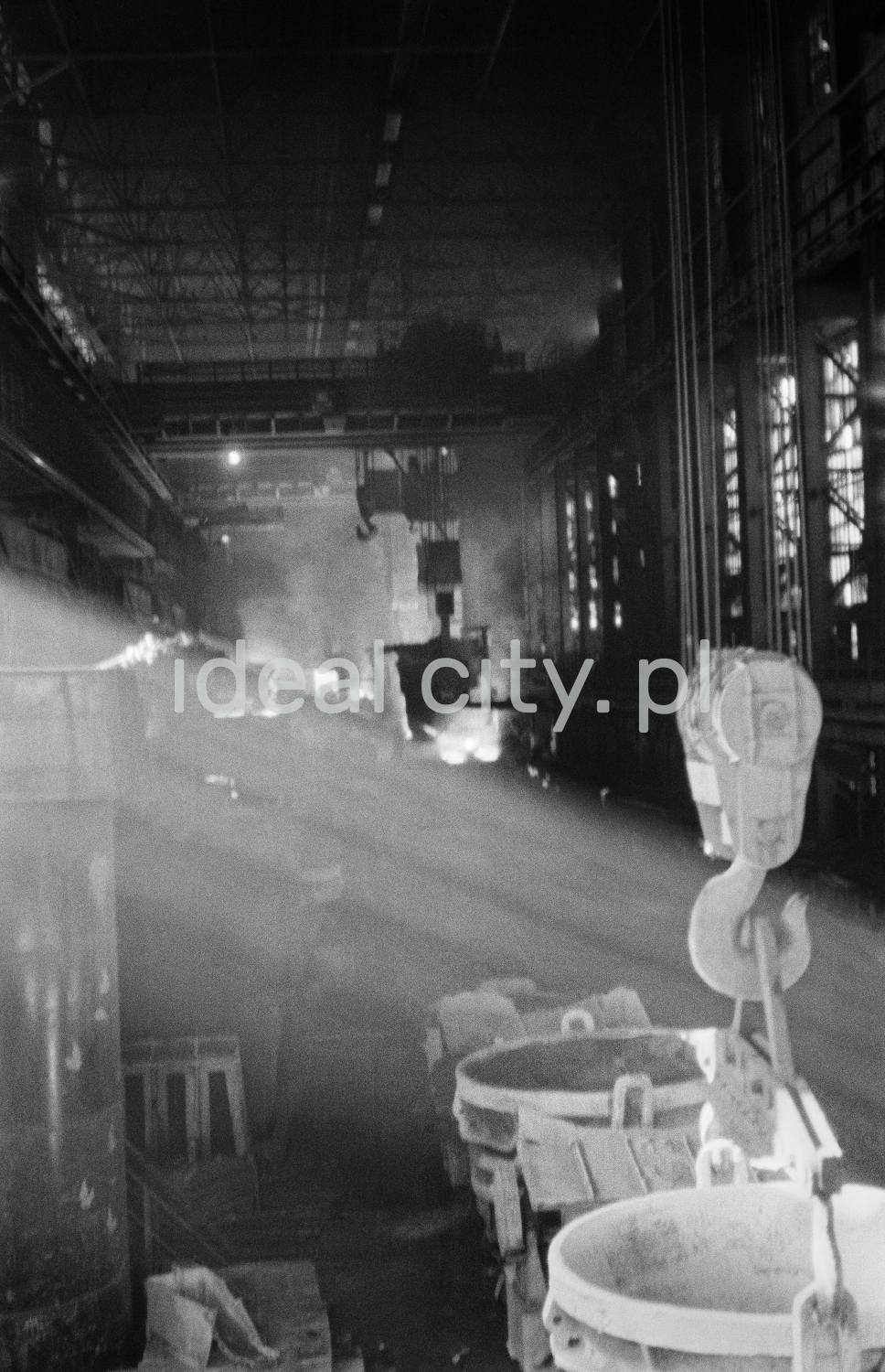 Sunbeams fall on a number of vats hanging in a dark hall.