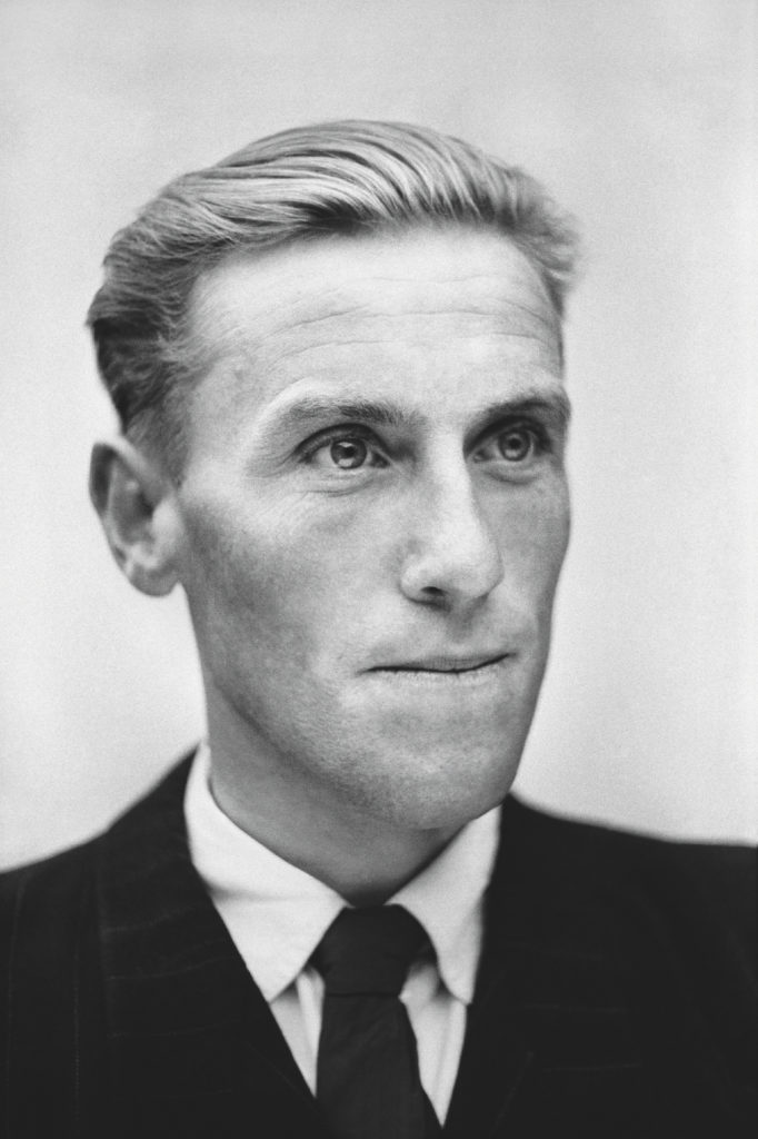 Czarno-biała fotografia w konwencji legitymacyjnej przedstawiająca mężczyznę w marynarce.