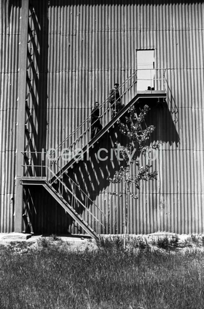 Two men climb the steel external stairs to the factory hall.