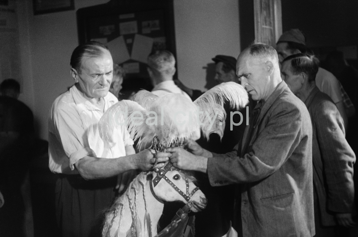 The two men adjust the head of a horse that is part of the outfit.