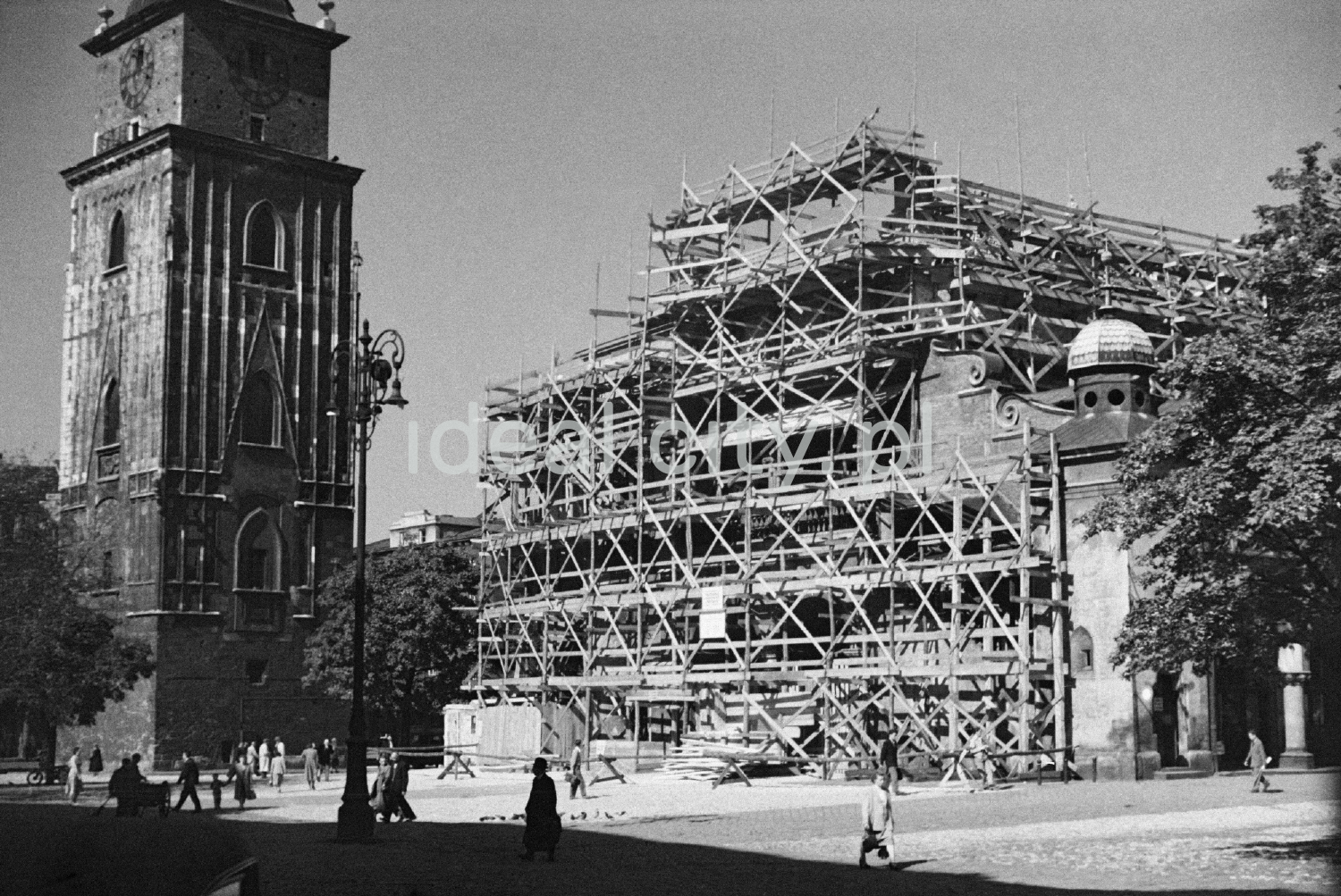 A view of the Sukiennice building hidden behind scaffolding, the Town Hall Tower on the left.