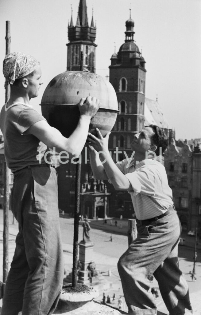 Two men attach a tin ball on the roof of the building, with a Gothic church in the background.