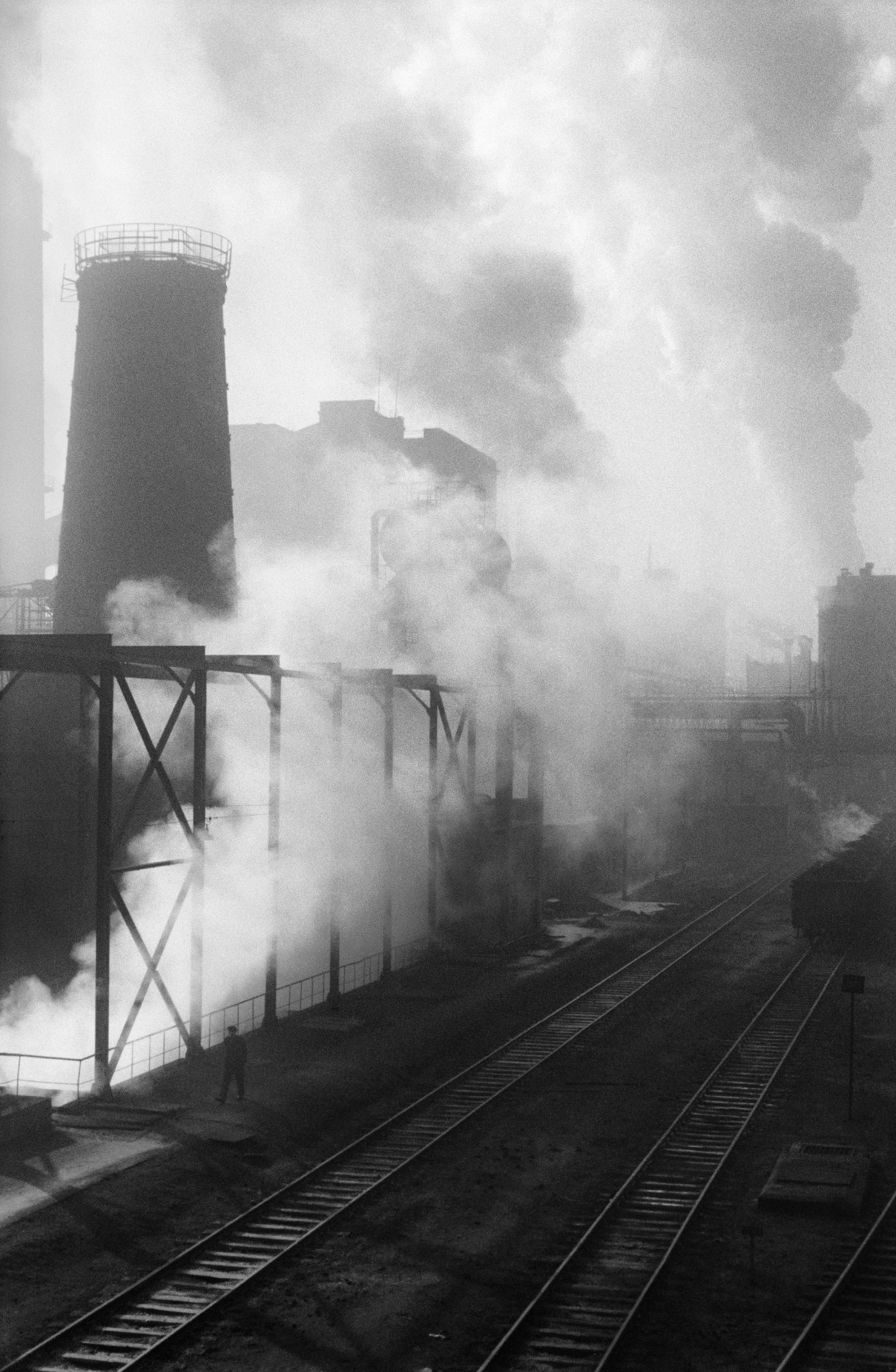 The shot shows a series of tall, intensely smoking chimneys.