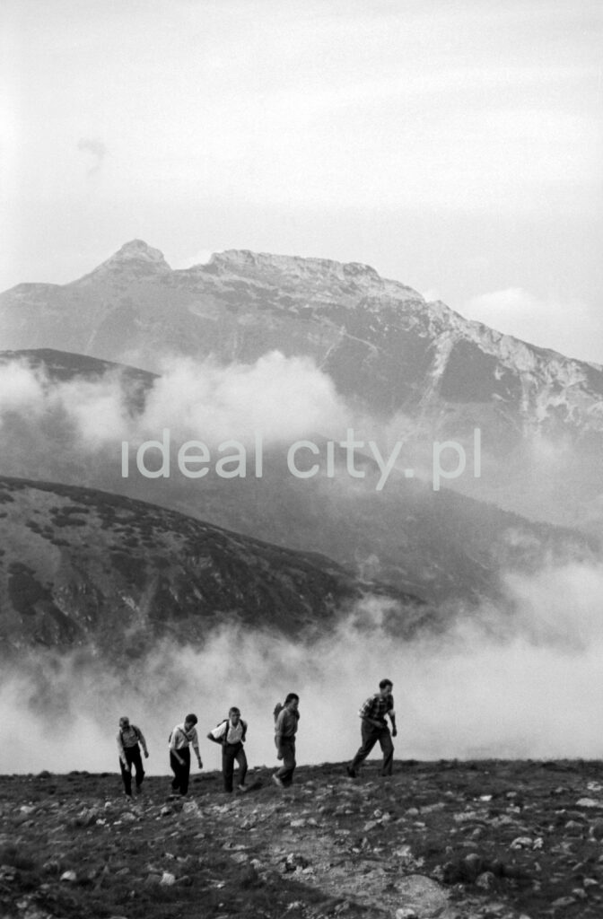 Tourists with backpacks go up the mountain trail, in the background the perspective of the Tatra peaks.