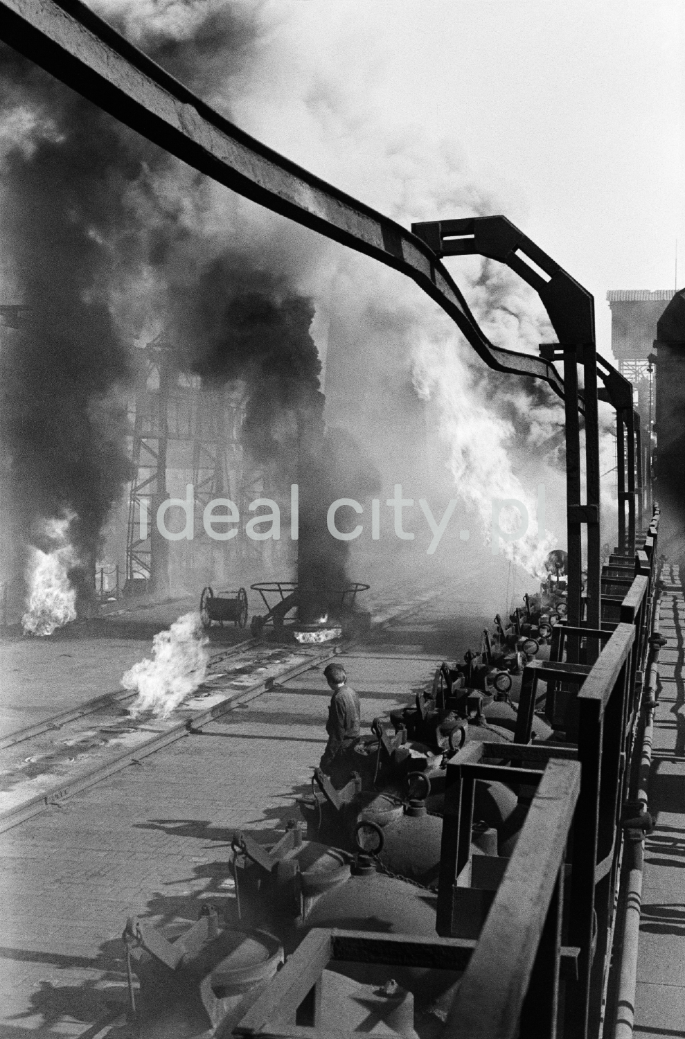 A man in workwear sits in the middle of the smoking installations of the coking plant.