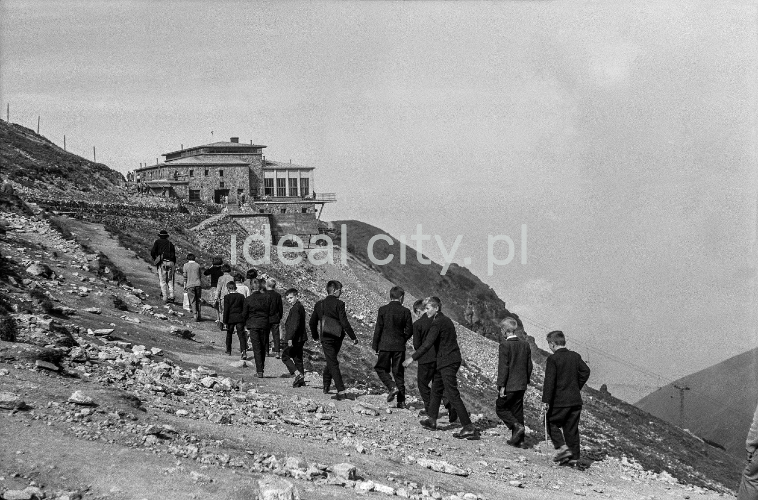 Young tourists in suits are heading towards the shelter on Kasprowy Wierch.