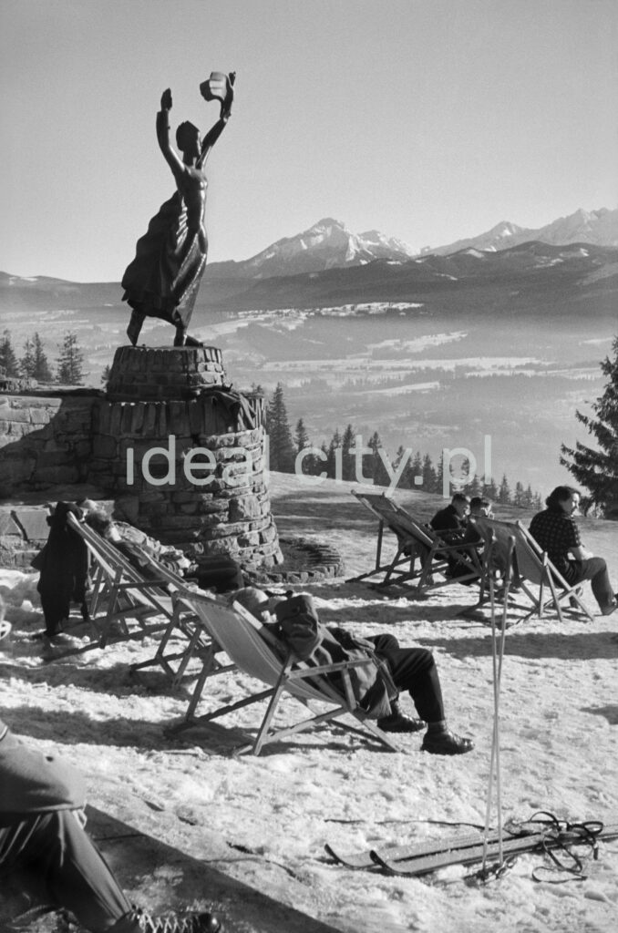 Winter patients relax in the sun on deckchairs at the top of the hill, in the background a panorama of mountain peaks.