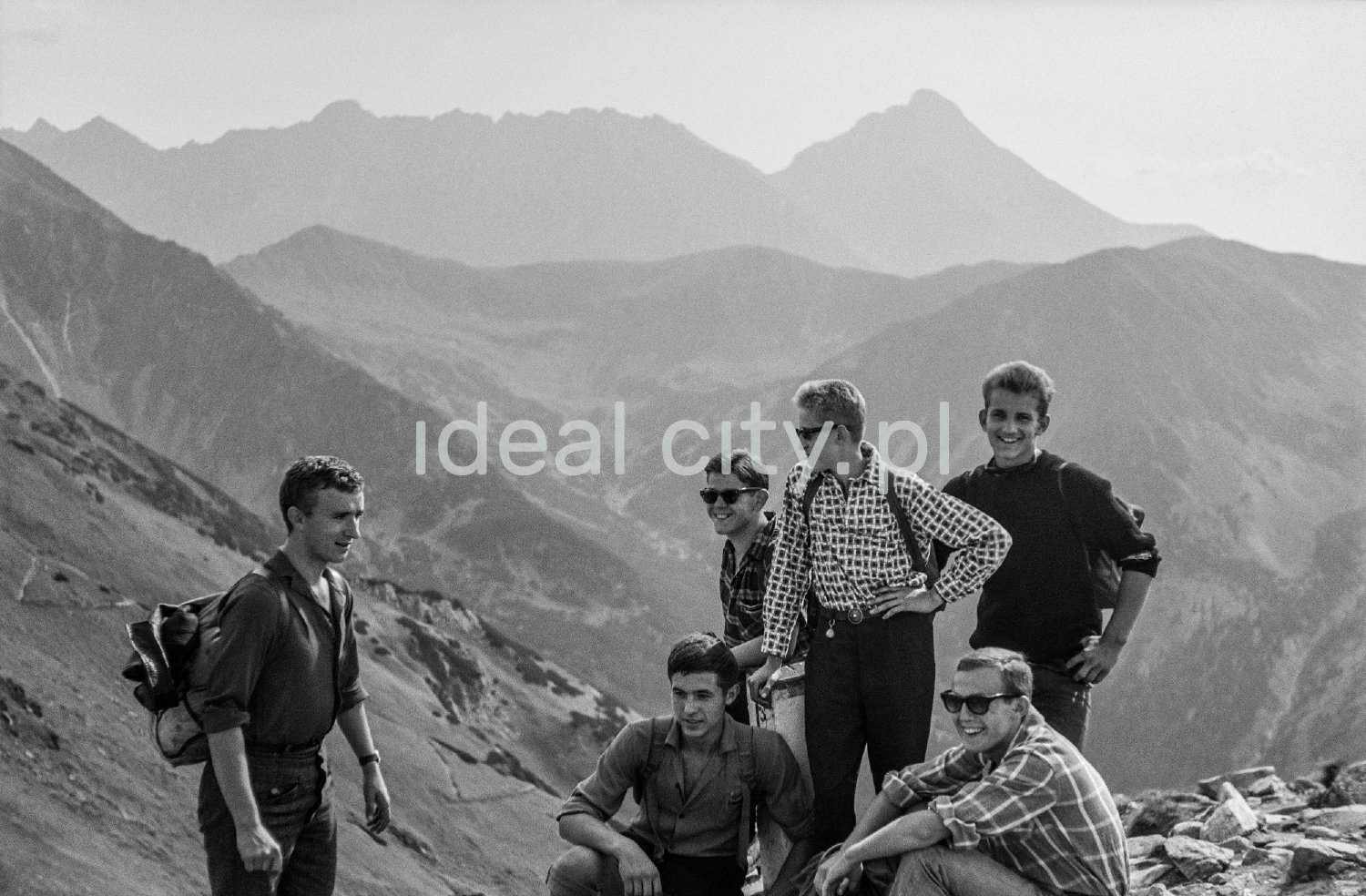 Tourists with backpacks rest on the edge of the rocky trail.