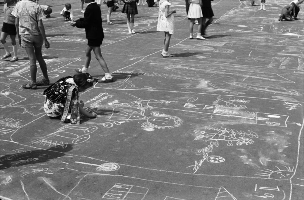 Children draw scenes related to the city and the factory with chalk on the pavement.