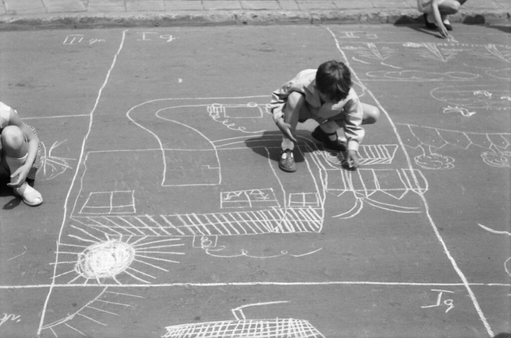 Children draw scenes related to the city and the factory with chalk on the pavement.