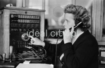 Wnętrze pierwszego urzędu pocztowego w Nowej Hucie, na osiedlu A-1 Północ (Willowe). Poczta została otwarta w połowie 1951 roku. Wystrój wnętrza, m.in. meble, kolumny pokryte marmurową okładziną, marmurowe blaty, zaprojektował Marian Sigmund. Pierwotnie w tym budynku (na piętrze) miał swoją siedzibę również Międzyzwiązkowy Klub Robotniczy. Na parterze znajdowały się punkty przyjęcia klientów, a na piętrze m.in. rozdzielnia oraz mieszkanie służbowe listonosza, który był jednocześnie stróżem. Listonosze dzielili się na miejskich i wiejskich, norma listonosza miejskiego wynosiła 2 tysiące mieszkańców. Na początku pracowało 7 listonoszy. W tle widoczne domy mieszkalne według projektów warszawskiego architekta Franciszka Adamskiego. Koniec lat 50. XXw. 

fot. Wiktor Pental/idealcity.pl

