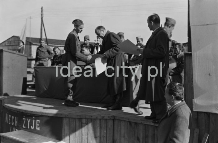 An awards ceremony; awards were given to young volunteers from the 91st and 92nd Brigades by the manager of the Department for Vocational Education at the Urban Construction Union. The ceremony took place at the site of today’s Kościuszkowskie Estate, where the volunteers (junacy) were stationed in 24 barracks. Ca. 1951.

Wręczenie nagród junakom z brygady nr 91 i 92 przez kierownika działu szkolenia zawodowego Zjednoczenia Budownictwa Miejskiego. Uroczystość odbyła się na terenie obecnego Osiedla Kościuszkowskiego, gdzie znajdowały się 24 baraki będące siedzibą junaków. Około 1951r.

Photo by Wiktor Pental/idealcity.pl

