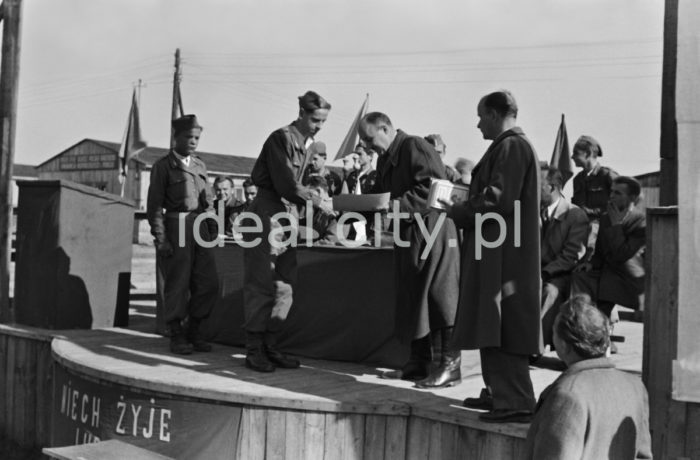 An awards ceremony; awards were given to young volunteers from the 91st and 92nd Brigades by the manager of the Department for Vocational Education at the Urban Construction Union. The ceremony took place at the site of today’s Kościuszkowskie Estate, where the volunteers (junacy) were stationed in 24 barracks. Ca. 1951.

Wręczenie nagród junakom z brygady nr 91 i 92 przez kierownika działu szkolenia zawodowego Zjednoczenia Budownictwa Miejskiego. Uroczystość odbyła się na terenie obecnego Osiedla Kościuszkowskiego, gdzie znajdowały się 24 baraki będące siedzibą junaków. Około 1951 r.

Photo by Wiktor Pental/idealcity.pl

