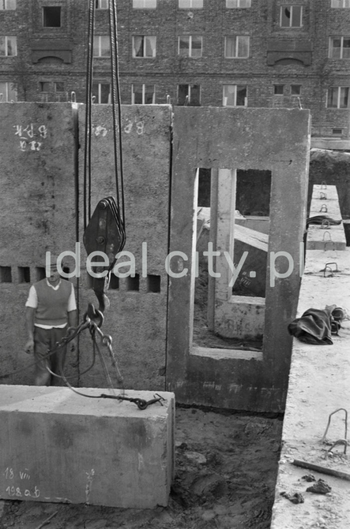 Robotnik mocujący elementy wielkopłytowe (betonowe bloki ścian) do stalowych lin ciągnika w żurawiu, na jednym z budynków mieszkalnych na nowohuckim osiedlu, lata 50.


fot. Wiktor Pental/idealcity.pl


