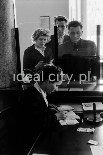 Wnętrze pierwszej poczty w Nowej Hucie na osiedlu A-1 Północ (Willowe). Została ona otwarta w połowie 1951 roku. Wystrój wnętrza, m.in. meble, kolumny pokryte marmurową okładziną, marmurowe blaty, zaprojektował Marian Sigmund. Pierwotnie w tym budynku (na piętrze) miał swoją siedzibę również Międzyzwiązkowy Klub Robotniczy. Na parterze znajdowały się punkty przyjęcia klientów, a na piętrze m.in. rozdzielnia oraz mieszkanie służbowe listonosza, który był jednocześnie stróżem. Listonosze dzielili się na miejskich i wiejskich, norma listonosza miejskiego wynosiła 2 tysiące mieszkańców. 

fot. Wiktor Pental/idealcity.pl

