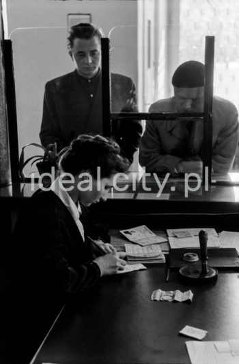 Wnętrze pierwszej poczty w Nowej Hucie na osiedlu A-1 Północ (Willowe). Została ona otwarta w połowie 1951 roku. Wystrój wnętrza, m.in. meble, kolumny pokryte marmurową okładziną, marmurowe blaty, zaprojektował Marian Sigmund. Pierwotnie w tym budynku (na piętrze) miał swoją siedzibę również Międzyzwiązkowy Klub Robotniczy. Na parterze znajdowały się punkty przyjęcia klientów, a na piętrze m.in. rozdzielnia oraz mieszkanie służbowe listonosza, który był jednocześnie stróżem. Listonosze dzielili się na miejskich i wiejskich, norma listonosza miejskiego wynosiła 2 tysiące mieszkańców. 
Połowa lat 50. XXw

fot. Wiktor Pental/idealcity.pl
