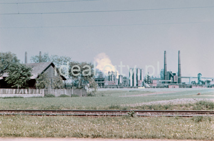 View from Pleszów towards Sinter Plant and Coking Works, Metallurgical Combine, Lenin Steelworks, 1960s.
In September 1954 Coking Oven Battery 1 began operating along with the first production line of the chemical section; Coking Over Battery 2 was activated in November, while Battery 6 only in 1958. The coking plant is an industrial plant for degasifying anthracite to obtain coke, coal gas, BTX, ammonia hydroxide, and coal tar (used mostly for manufacturing pesticides, medicines, dyes, modelling clay, and explosives). The sinter plant is where ores are sintered. The plant comprises several buildings housing stockpiles of powdered materials, cranes, conveyors, and high chimneys. Sinter plants prepare ore charges (also obtained from scrap) for blast furnaces, consecutively mixed with coke.

Widok od strony Pleszowa w kierunku Aglomerowni i Zakładu Koksochemicznego kombinatu metalurgicznego Huty im. Lenina, lata 60.
We wrześniu 1954 roku została uruchomiona bateria koksownicza nr 1 wraz z pierwszą nitką produkcyjną wydziału chemicznego, w listopadzie uruchomiono baterię koksownicza nr 2, a baterię nr 6 w 1958 roku. Koksownia to zakład przemysłowy, w którym w piecach koksowniczych poddaje się odgazowaniu węgiel kamienny i otrzymuje się koks, gaz koksowniczy, benzol, wodę amoniakalną i smołę pogazową (wykorzystywaną między innymi do produkcji środków ochrony roślin, lekarstw, barwników, mas plastycznych oraz materiałów wybuchowych). Aglomerownia to spiekalnia rud. Jest to zespół budynków ze składowiskiem materiałów sypkich, suwnicami oraz systemem taśmociągów i wysokimi kominami. W spiekalni przygotowuje się wsad rudy (pozyskiwanej także ze złomu do wielkiego pieca), kolejno mieszany z koksem.

Photo by Wiktor Pental/idealcity.pl

