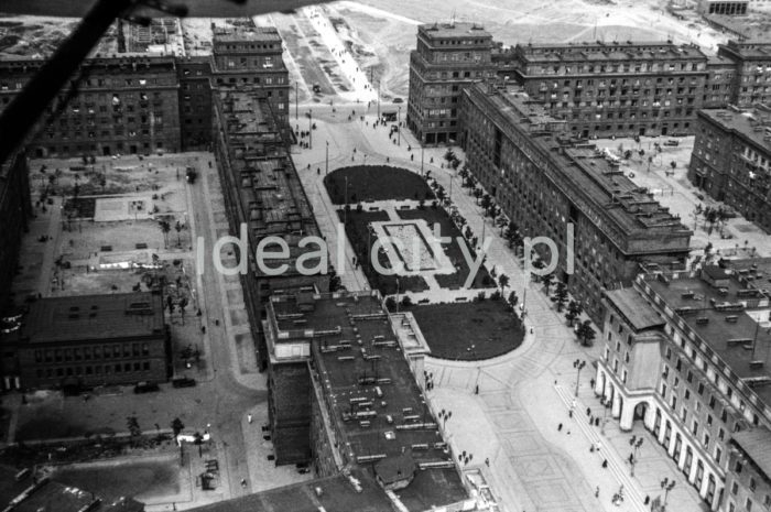 An aerial photograph depicting buildings in the vicinity of Plac Centralny, right: Centrum B (B-31) Estate, left: Centrum C (C-31) Estate and the wide Aleja Róż with a relaxation square between them. The detached building on the Centrum C Estate was the seat of the Chief Technical Organisation (it now houses the Technical Club and the Nowa Huta Branch of the Polish Electrician Society). Late 1950s.

Fotografia Lotnicza przedstawia fragmentaryczne zabudowania dwóch osiedli w okolicy Placu Centralnego, po prawej Centrum B (B-31), po lewej Centrum C (C-31) oraz rozdzielającą je obszerną Aleję Róż z wypoczynkowym skwerem pośrodku. 
W zabudowie osiedla Centrum C widoczny jest wolnostojący budynek, który był siedzibą Naczelnej Organizacji Technicznej (obecnie mieści się w nim Klub Technika oraz Nowohucki Oddział Stowarzyszenia Elektryków Polskich), koniec l. 50. XX w.

Photo by Henryk Makarewicz/idealcity.pl

