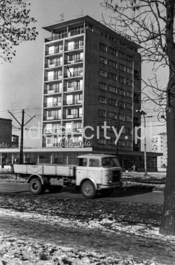 The Centrum D (D-31) Estate, view from Plan 6-letni Alley (Six-Year-Plan Alley; now Jana Pawła II Alley). Block nr 7 (now 8), nicknamed “helicopter,” designed by Kazimierz Chodorowski and Stefan Golonka. It was built in the new “post-thaw” style, close to social realist buildings in Plac Centralny. The ten-storey block was surrounded at the ground level by a glass-walled pavilion housing a variety of shops, including a sweet shop officially called Ciastkarnia Bambo. Apart from flats with big windows and loggias, it held spacious artistic studios. One of the studios was used by Henryk Makarewicz, who took this photograph and also lived there. 1960s.

Osiedle Centrum D (D-31), widok od strony alei Planu 6-letniego (obecnie aleja Jana Pawła II).  Blok nr 7 (obecnie nr 8) czyli tzw. helikopter.. Autorami projektu byli Kazimierz Chodorowski i Stefan Golonka. Został wybudowany w nowej, „poodwilżowej” formie, tuż przy socrealistycznej zabudowie placu Centralnego. Dziesięciopiętrowy punktowiec w poziomie parteru otoczony został pawilonem handlowo-usługowym o szklanej elewacji. Mieściła się w nim m.in.: cukiernia, która oficjalnie zwana była „Ciastkarnią Bambo”. Poza lokalami mieszkalnymi z dużymi oknami i loggiami, posiadał on obszerne pracownie artystyczne. W bloku tym miał pracownie i mieszkał autor fotografii Henryk Makarewicz, l. 60. XX w.

Photo by Henryk Makarewicz/idealcity.pl
