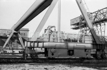 Kombinat metalurgiczny im. Lenina, most przeładunkowy na składowisku surowców z suwnicą bramową z taśmociągiem, lata 60.
Suwnica bramowa składa się z pomostu zawieszonego na dwóch bocznych mostach, wiążących dwie lub więcej bram. Każda z bram wyposażona jest w podwozie typu szynowego lub kołowego. Po pomoście przesuwa się cięgnik.

fot. Henryk Makarewicz/idealcity.pl

