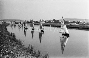 Parada żaglówek na Wiślem na wysokości Nowej Huty. Początki żeglarstwa w Krakowie-Nowej Hucie sięgają 1955r. Utworzono wówczas Zakładowy Klub Morski z czterema sekcjami: kajakową, wioślarską motorowodną i żeglarską przy Zjednoczeniu Przemysłowym Budowy Huty im. Lenina. Rozpoczęto również budowę przystani wodnej Nad Wisłą u wylotu ulicy Klasztornej.
22.07.1955 - uroczyste otwarcie przystani w nowo wybudowanych hangarach, a na wodę spłynęły oprócz kajaków 4 jachty: Omega, dwa Finny i BM.
W 1959r. nastąpiła zmiana nazwy Klubu na Yacht Klub „Budowlani