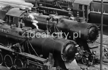 Parowozy na terenie Parowozowni Huty im. Lenina, przełom lat 50. i 60.
Podstawowym środkiem przewozu w Hucie im. Lenina był transport kolejowy. Do 1970 roku zajmowały się tym cztery wydziały przewozowe, w skład których wchodziły służby przewozowo-wagonowe oraz służby trakcyjne. Wewnątrz kombinatu znajdowało się kilkanaście stacji kolejowych, przez które odbywał się przepływ ładunków i wagonów kolejowych. Pierwsza Parowozownia dla 40 parowozów powstała w 1952 roku. Początkowo materiały na budowę były wożone linią kocmyrzowską. Na północ od stacji Czyżyny wybudowano nawet wielki plac przeładunkowy z niezbędnymi bocznicami, ale możliwości tej skromnej, lokalnej kolei były niewystarczające. Dla potrzeb przyszłego kombinatu potrzebna była nowa linia, którą wyprowadzono od linii Warszawskiej ze stacji Batowice. Wybudowana w 1952 roku nowa trasa przecinała starą „kocmyrzówkę” (w kierunku na Kocmyrzów), dlatego na linii kocmyrzowskiej dwa wiadukty. Pierwsza surówka z wielkiego pieca Huty im. Lenina popłynęła w 1954 roku. W międzyczasie na terenie kombinatu powstała bardzo gęsta sieć bocznic kolejowych. Nieopodal kombinatu zbudowano ogromną stację zestawczą. Linię prowadzącą do huty przedłużono od stacji Batowice na zachód w kierunku Śląska, a także na południowy wschód, gdzie nowym mostem na Wiśle kolej docierała do stacji Podłęże, na której powstał bezkolizyjny węzeł. Na połączeniu z linią Warszawską zbudowano łącznicę, pozwalającą na bezpośrednią jazdę od strony huty na północ. Tę nową, towarową magistralę, omijającą Kraków od północy, nazwano „dużą obwodnicą”.

fot. Henryk Makarewicz/idealcity.pl



