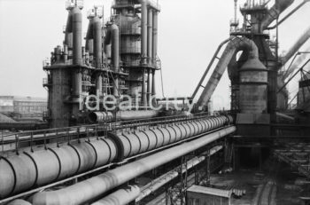 Blast Furnace Plant at the Lenin Metallurgical Combine. Fragment of technical system and hot stoves. By-products of smelting steel in the blast furnace include slag and blast furnace gas (a mixture of carbon monoxide, nitrogen and carbon dioxide). Burnt in hot stoves, the gas heats blasted air considerably boosting the efficiency of the process. Early 1960s.

Wydział Wielkich Pieców w kombinacie metalurgicznym im. Lenina. Widoczny fragment instalacji technicznej oraz nagrzewnice. Podczas procesu wytapiania stali w wielkim piecu produktem ubocznym prócz żużla jest również gaz wielkopiecowy (mieszanina tlenku węgla, azotu i dwutlenku węgla). Spalany w nagrzewnicach gaz służy do ogrzewania wdmuchiwanego powietrza, co znacznie podnosi efektywność procesu, początek lat 60. 

Photo by Henryk Makarewicz/idealcity.pl
