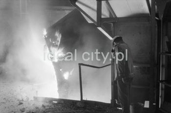 Kombinat metalurgiczny im. Lenina, wnętrze hali Stalowni Konwertorowej, wyciąganie kadzi, II połowa lat 60.
Stalownię uruchomiono w lutym 1966 roku. Była pierwszą tego typu stalownią w Polsce. Budynek główny obejmował halę konwerterów z dwoma konwertorami, halę wsadu oraz dwie hale odlewnicze. Wsad metaliczny stanowił 70% płynnej surówki i ok. 30% złomu. Surówka ciekła dostarczana była z mieszalników na surówkowozach, wyposażonych w kadzie. Odlewanie stali odbywało się do kadzi odlewniczych, umieszczonych na napędzanym elektrycznie wozie stalowniczym, jeżdżącym w poprzek hal odlewniczych. Po ściągnięciu wlewnic w odpowiedniej hali, wlewki w stanie gorącym przekazywano do pieców wgłębnych walcowni wstępnych. Żużel wywożono do kafaru na żużlowozach.

fot. Henryk Makarewicz/idealcity.pl



