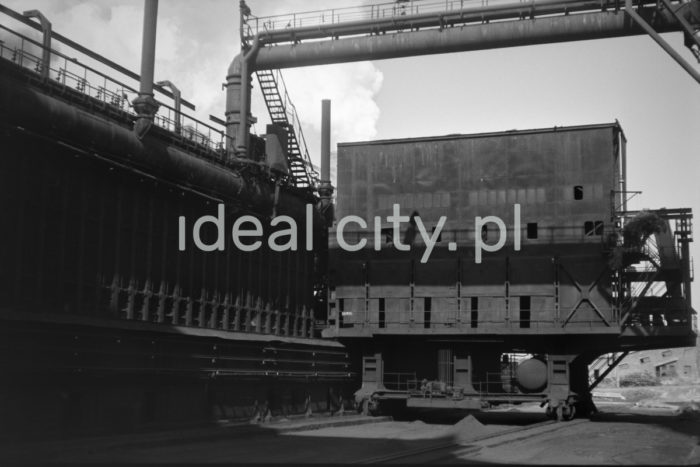 Lenin Metallurgical Combine, coke oven battery. 1960s.
Coking Plant No. 1 was constructed in 1954-6. The eight-battery group of coke ovens included two sets four batteries each and two screening units. Gas was steered from the battery to sections of condensing and recovering coal derivates no. 1 with a later extension housing a Thylox gas desulfator. Condensing and purifying gas produced tar, ammonia water, BTX – pyrimidines and sulphur. The first stage of the construction of Coking Plant no. 2 was finished in 1966. There were 12 coke oven batteries operating in the 1970s.

Kombinat metalurgiczny im. Lenina, bateria koksownicza, lata 60.
Koksownia nr 1 została wybudowana w latach 1954-1956. Ośmiobateryjny blok pieców koksowniczych składał się z dwóch zespołów po cztery baterie oraz dwóch sortowni. Gaz z baterii kierowany był do oddziałów kondesacji i odzysku węglopochodnych nr 1 z dobudowaną odsiarczalnia gazu systemem Thylox. Na drodze kondensacji i oczyszczania gazu otrzymywano smołę, wodę amoniakalną, benzol – zasady pirydynowe oraz siarkę. Pierwszy etap Koksowni nr 2 wybudowano w 1966 roku. W latach 70. działało 12 baterii koksowniczych.

Photo by Henryk Makarewicz/idealcity.pl

