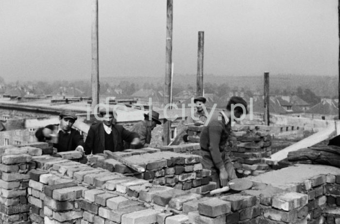 Brygada murarzy przy wznoszeniu domów na Osiedlu Zielonym, w tle Osiedle Sportowe. Budowę najstarszych osiedli rozpoczęto w 23 czerwca 1949 roku właśnie od jej południowo-wschodniej części. Rozpoczęto ją na osiedlach A-1 Północ i A-1 Południe (Willowe i Wandy) oraz A-O (Na Skarpie). Autorami projektu urbanistycznego tych osiedli byli: Tadeusz Ptaszycki, Bolesław Skrzybalski, Adam Fołtyn i Zbigniew Sieradzki. Domy budowano według projektów warszawskiego architekta Franciszka Adamskiego. Były to typowe budynki jedno lub dwupiętrowe z dwuspadowymi dachami z czerwonej dachówki i bez punktów usługowych i biurowych na parterze. Domy Adamskiego wzniesiono również w następnym roku w części osiedla C-2 Północ (Krakowiaków). W przeciwieństwie do domów budowanych na osiedlach A-1 usytuowano je nie w liniach prostych, ale przy wijących się uliczkach. Pierwsze domy rozpoczęto budować bez planów architektonicznych i urbanistycznych nowego miasta, gdyż pracownia projektowa Tadeusza Ptaszyckiego była w studium organizacyjnym i część projektantów przebywała w Warszawie, gdzie utworzono przy Ministerstwie Budownictwa Centralne Biuro Projektów i Studiów Budownictwa Osiedlowego Zakładu Osiedli Robotniczych (CBPiSBO ZOR)  Do biura przy ul. 1 Maja 1 (obecnie ul. biskupa J. Dunajewskiego) w Krakowie wprowadzono się 1 stycznia 1950 roku oficjalnie inaugurując działalność Biura ZOR, 1949 rok.

fot. Wiktor Pental/idealcity.pl
