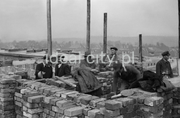 Brygada murarzy przy wznoszeniu domów na Osiedlu Zielonym, w tle Osiedle Sportowe. Budowę najstarszych osiedli rozpoczęto w 23 czerwca 1949 roku właśnie od jej południowo-wschodniej części. Rozpoczęto ją na osiedlach A-1 Północ i A-1 Południe (Willowe i Wandy) oraz A-O (Na Skarpie). Autorami projektu urbanistycznego tych osiedli byli: Tadeusz Ptaszycki, Bolesław Skrzybalski, Adam Fołtyn i Zbigniew Sieradzki. Domy budowano według projektów warszawskiego architekta Franciszka Adamskiego. Były to typowe budynki jedno lub dwupiętrowe z dwuspadowymi dachami z czerwonej dachówki i bez punktów usługowych i biurowych na parterze. Domy Adamskiego wzniesiono również w następnym roku w części osiedla C-2 Północ (Krakowiaków). W przeciwieństwie do domów budowanych na osiedlach A-1 usytuowano je nie w liniach prostych, ale przy wijących się uliczkach. Pierwsze domy rozpoczęto budować bez planów architektonicznych i urbanistycznych nowego miasta, gdyż pracownia projektowa Tadeusza Ptaszyckiego była w studium organizacyjnym i część projektantów przebywała w Warszawie, gdzie utworzono przy Ministerstwie Budownictwa Centralne Biuro Projektów i Studiów Budownictwa Osiedlowego Zakładu Osiedli Robotniczych (CBPiSBO ZOR)  Do biura przy ul. 1 Maja 1 (obecnie ul. biskupa J. Dunajewskiego) w Krakowie wprowadzono się 1 stycznia 1950 roku oficjalnie inaugurując działalność Biura ZOR.

fot. Wiktor Pental/idealcity.pl

