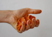 an open hand holds a crushed piece of clay