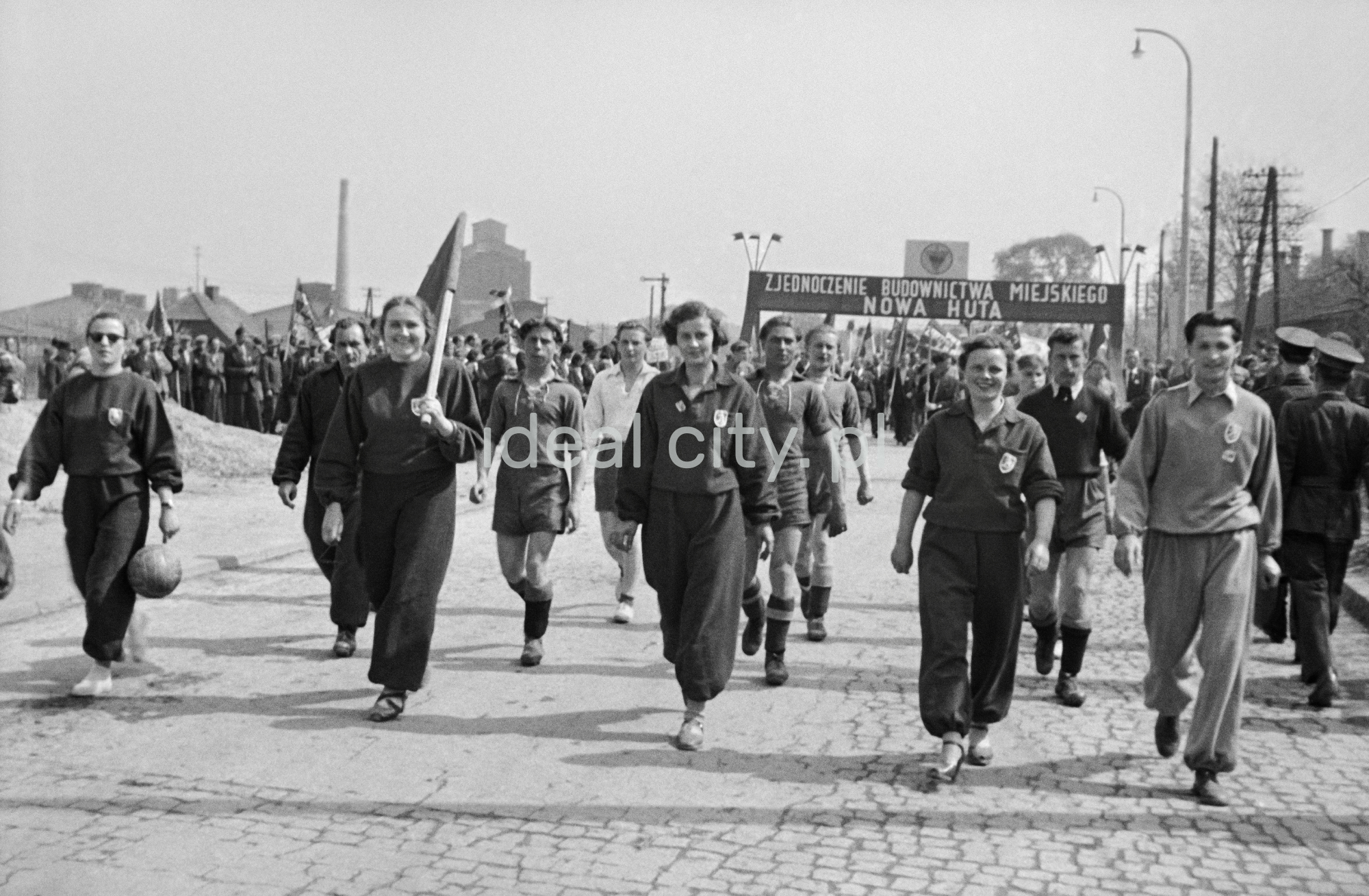Odświętnie ubrani ludzie maszerują z transparentami.