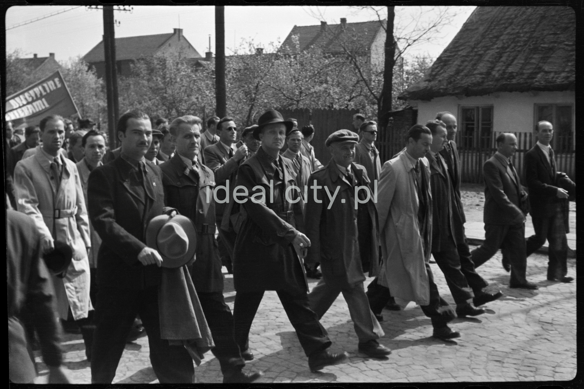 Odświętnie ubrani ludzie idą dynamicznie w pochodzie.