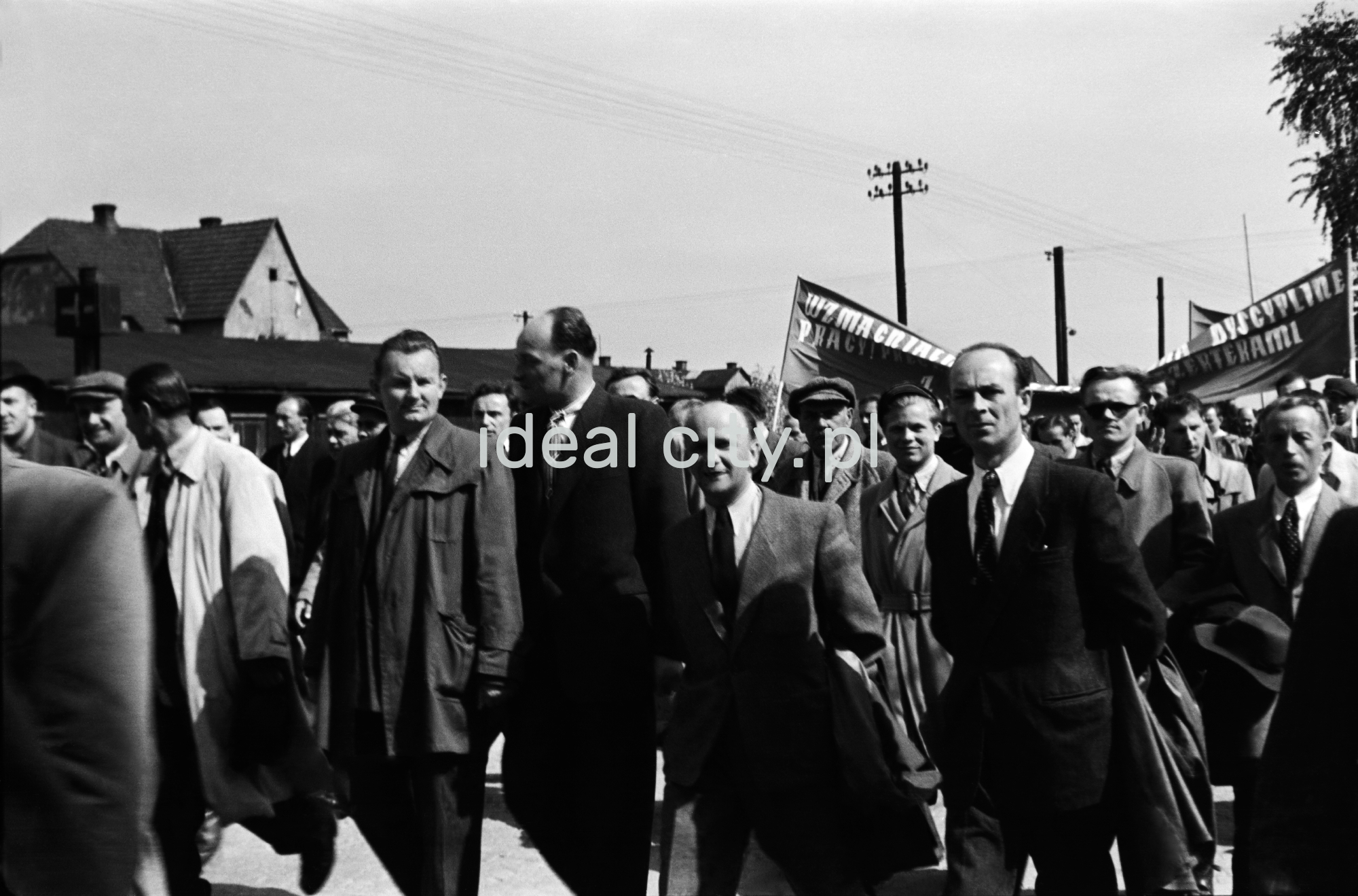 Odświętnie ubrani ludzie idą dynamicznie w pochodzie.